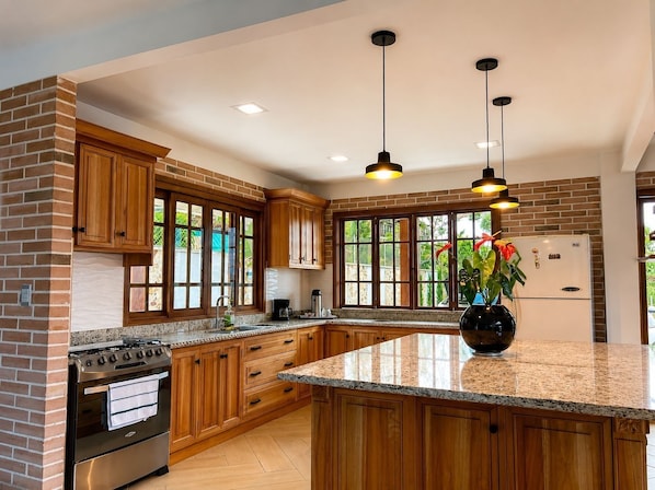 A kitchen with wooden cabinets, a granite countertop, a stainless steel oven, and a refrigerator.