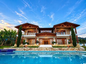 A large, two-story house with a swimming pool in front.