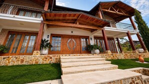 Une maison à deux étages avec une façade en pierre, des poutres en bois et une grande porte d’entrée.
