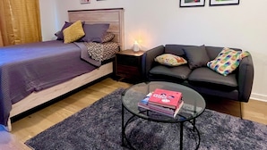 A bedroom with a bed, a sofa, a coffee table, and framed pictures on the wall. - South Austin Condo (Austin)