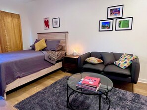 Un dormitorio con cama, sofá, mesa de centro y cuadros en la pared.