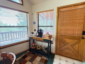 Ein Zimmer mit Holztür, einer Kaffeestation mit Kaffeemaschine, Gläsern und einem dekorativen Gegenstand.