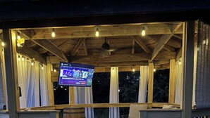 Una terrassa de fusta amb una pantalla de televisió, seients exteriors i una escala que hi mena.