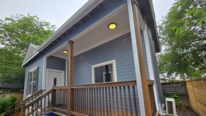 Ein Haus mit Veranda, Grill und Holzterrasse.