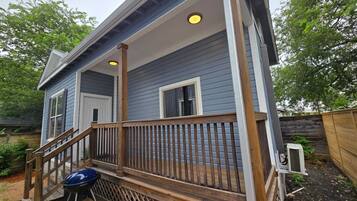 A house with a porch, a grill, and a wooden deck.