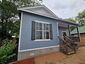 A single-story house with a porch, a window with shutters, and a small staircase leading to the entrance. - Casita 2 minutes from the Alamodome (San Antonio)