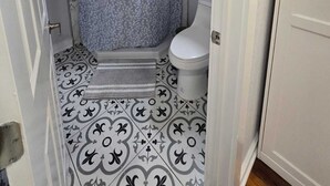 Ein Badezimmer mit Dusche, Toilette und Fliesenboden mit Muster.