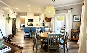 A modern kitchen with white cabinets, a central island with blue bar stools, and a hanging light fixture. - 3-bedroom pet-friendly house in Grover Beach - 2 miles from the Beach (Grover Beach)