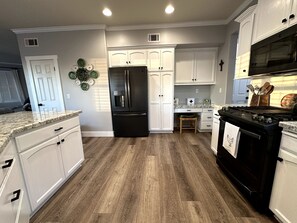 A kitchen with white cabinets, a black refrigerator, a wooden countertop, and a stove. - 3-bedroom pet-friendly house in Grover Beach - 2 miles from the Beach (Grover Beach)