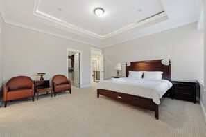 Ein Hotelzimmer mit einem großen Bett, zwei Sesseln, einem Nachttisch und einer Lampe.