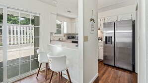 A modern kitchen with a stainless steel refrigerator, white cabinetry, and a large island with bar stools.