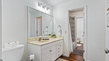 Een badkamer met toilet, wastafel, spiegel en een douchehoek.