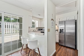 Una cocina moderna con un refrigerador de acero inoxidable, armarios blancos y una isla grande con taburetes de bar.