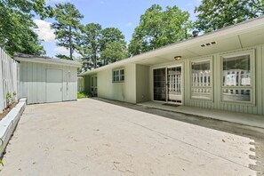Ein eingeschossiges Gebäude mit einer überdachten Terrasse, einer Garage und einer Haustür mit Fensterteil.