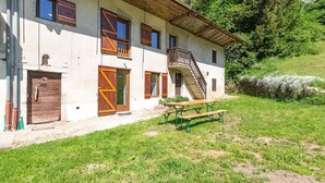 A rustic building with a wooden staircase, a front door, and a picnic table. - La Correrie des Chartreux (AILLON LE JEUNE)