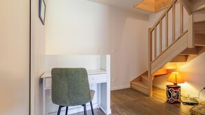 A room with a desk, chair, wooden staircase, and a lamp. - La Correrie des Chartreux (AILLON LE JEUNE)