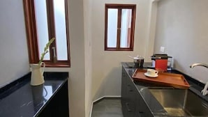 Cocina estrecha con encimera negra, un lavabo y una ventana con marcos de madera.