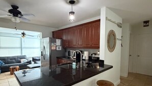 A modern kitchen with a central island, bar stools, and a dining area with a sofa. - Waterfront~Boat Deck, Pool home near Hard Rock~FLL Airport & FIFA World Cup (Fort Lauderdale)