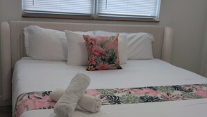 A bed with white bedding, a floral pillow, and a rolled towel. - Waterfront~Boat Deck, Pool home near Hard Rock~FLL Airport & FIFA World Cup (Fort Lauderdale)