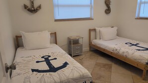 Two single beds with anchor-themed bedding, a small bedside table, and a window with blinds. - Waterfront~Boat Deck, Pool home near Hard Rock~FLL Airport & FIFA World Cup (Fort Lauderdale)