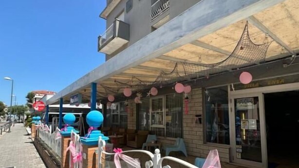 Un immeuble doté d’un balcon, un magasin avec une devanture vitrée et un trottoir pavé.