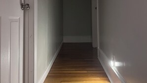 A hallway with wooden flooring, white walls, and a door on the left. - Clean & Cozy Private room - 3 floor_R 1 (Worcester)