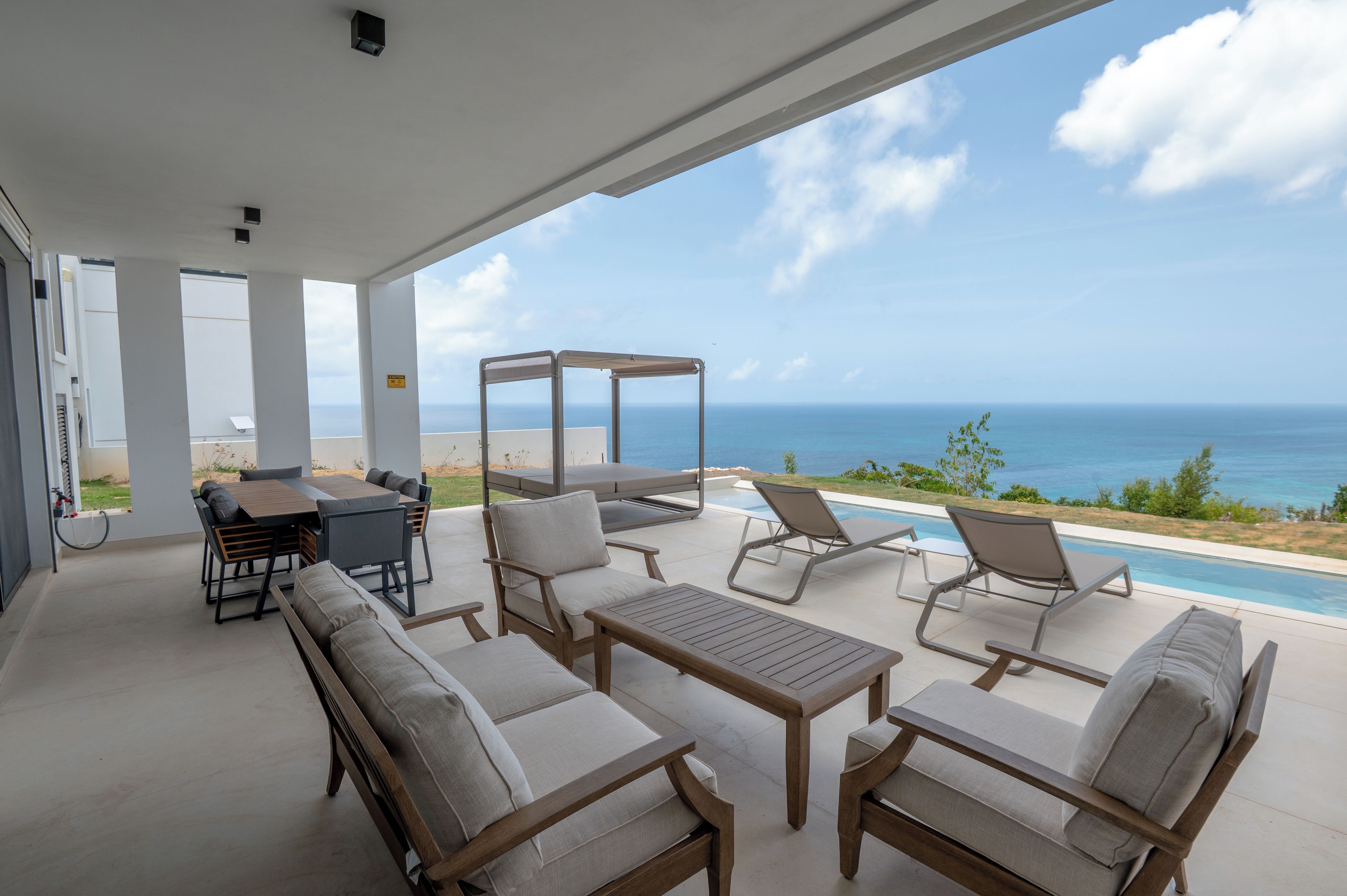 An outdoor patio with a pool, lounge chairs, and a dining table.