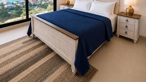 A bedroom with a large window, a bed, a nightstand, a ceiling fan, and a view of the ocean and buildings. - Modern Pelican St. Maarten Escape with Pool, Views & Outdoor Lounge (Cole Bay)