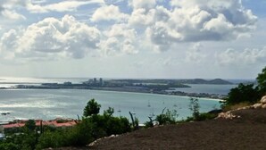 A coastal landscape with a view of the sea, boats, and distant buildings. - Modern Pelican St. Maarten Escape with Pool, Views & Outdoor Lounge (Cole Bay)