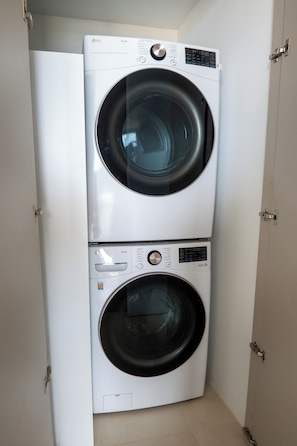 Eine übereinander gestellte Waschmaschine und ein Trockner in einem Hauswirtschaftsraum.