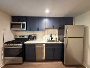 A compact kitchen with dark cabinets, a stainless steel refrigerator, a microwave, a stove, and a dishwasher. - Private Saratoga retreat - Travel Nurses, Business professionals, Professors (Gansevoort)