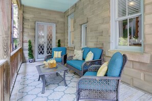 A covered patio with wicker furniture, a glass table with drinks, and a view through a window. - Spacious Historic 2BR w/ Courtyard, Parking, Walk to Forsyth Park (Savannah)