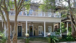 A two-story house with a front porch, a balcony, and a staircase leading to the second floor. - Spacious Historic 2BR w/ Courtyard, Parking, Walk to Forsyth Park (Savannah)