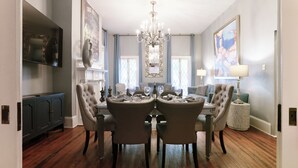 A dining room with a chandelier, a television, and a fireplace. - Spacious Historic 2BR w/ Courtyard, Parking, Walk to Forsyth Park (Savannah)