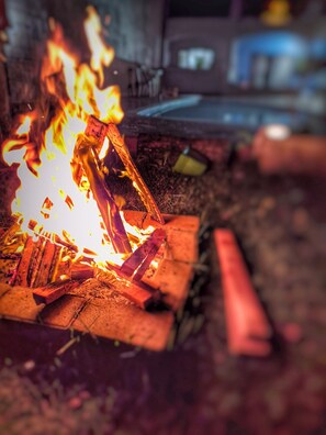 A campfire with logs and flames. - Cozy suite in Peruíbe, SP (Peruíbe)