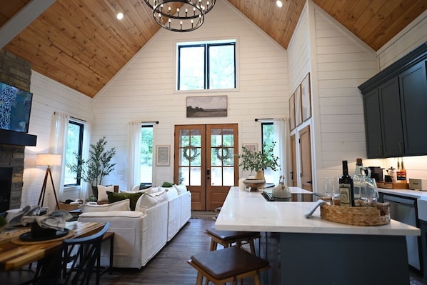 A spacious kitchen with a wooden ceiling, a central island, and a dining area with a white table and chairs. - Summit Sky: Charming Luxury Cabin with Treetop Views in Hochatown, Broken Bow (Broken Bow)