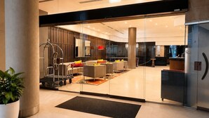 A modern lobby with glass doors, a reception desk, and seating area. - Queen Street CBD Stay with Balcony and Amenities (Brisbane City)