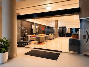 Eine moderne Lobby mit Glastüren, einer Rezeption und einer Sitzecke.