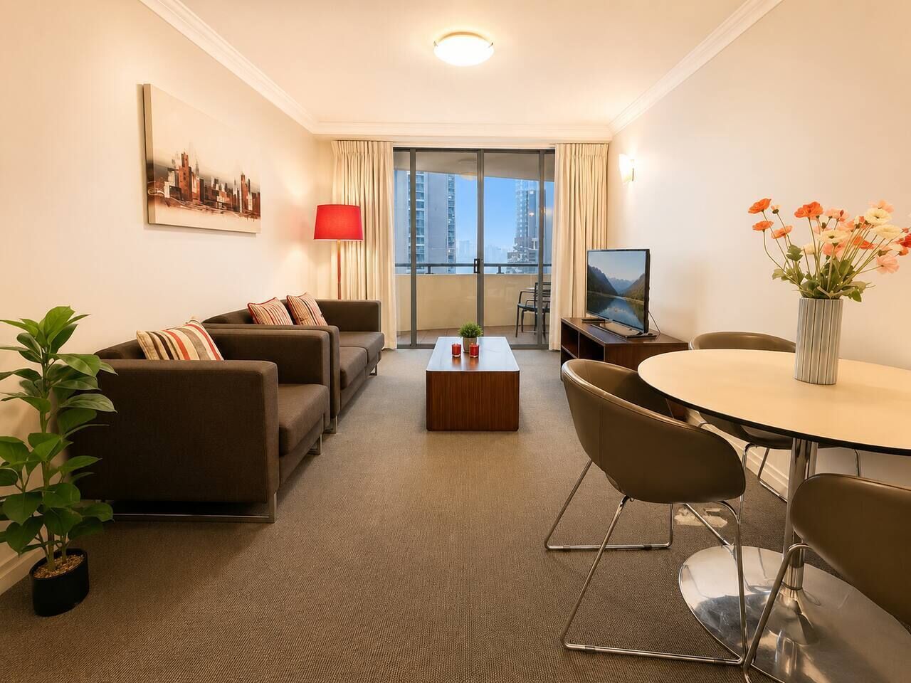 A modern hotel room with a sofa set, a dining table, a coffee table, a TV, and a large window with curtains.