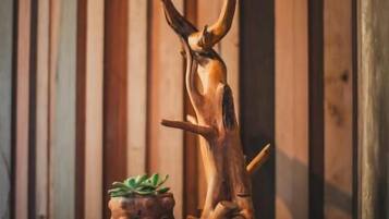 Una escultura de madera con una planta sobre un tocador frente a una pared de madera.