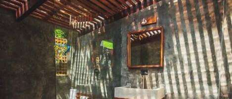 Un baño con tocador de madera, un espejo, un inodoro y una cabina de ducha de vidrio.