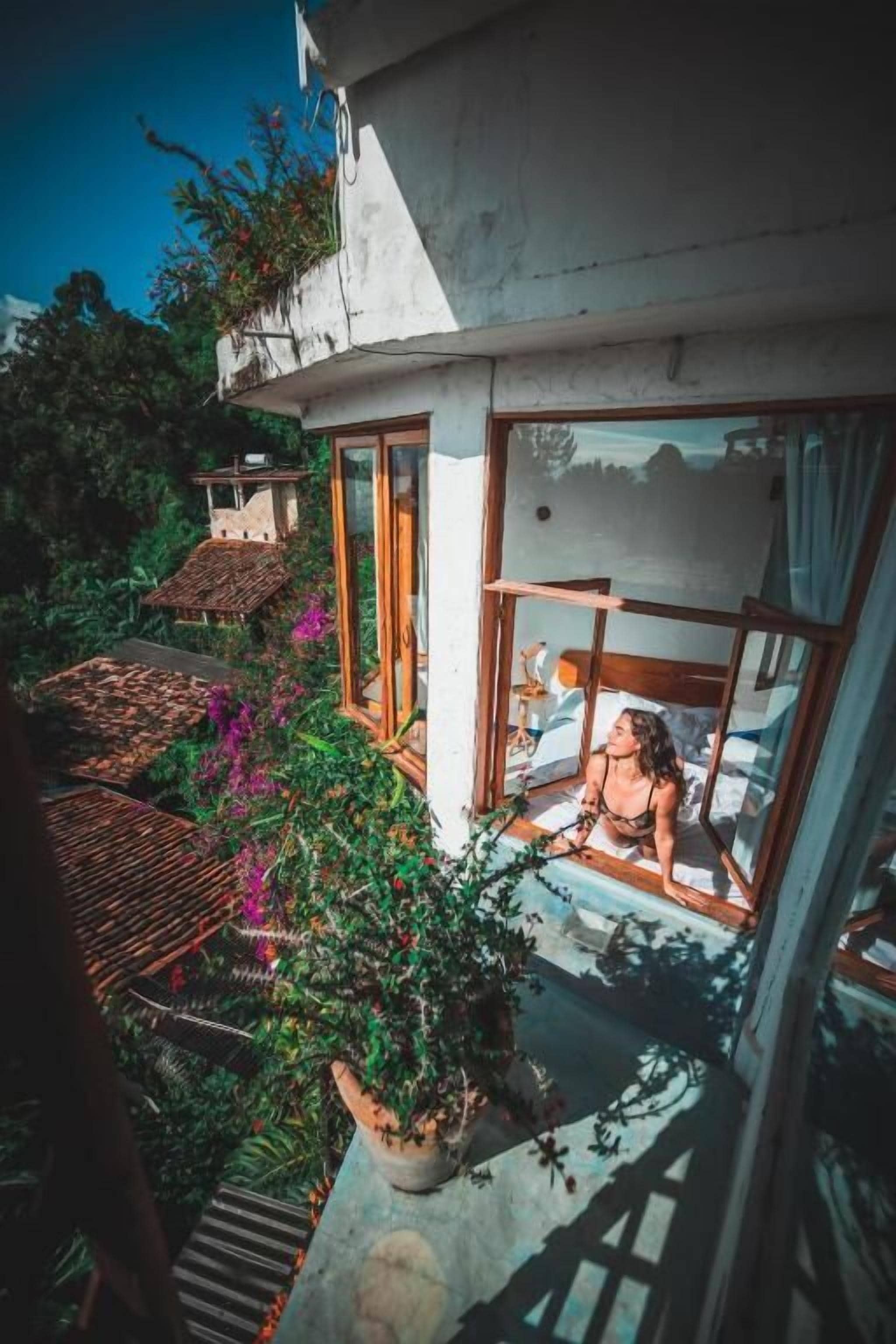 A modern house with a balcony, potted plants, and a view of the surrounding area.