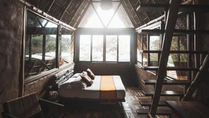 Ein Zimmer mit einem Bett, einem Fenster, einer Leiter und einem Stuhl.