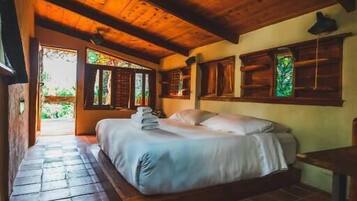 A wooden ceiling, a bed with pillows, a nightstand, and a window with a view.