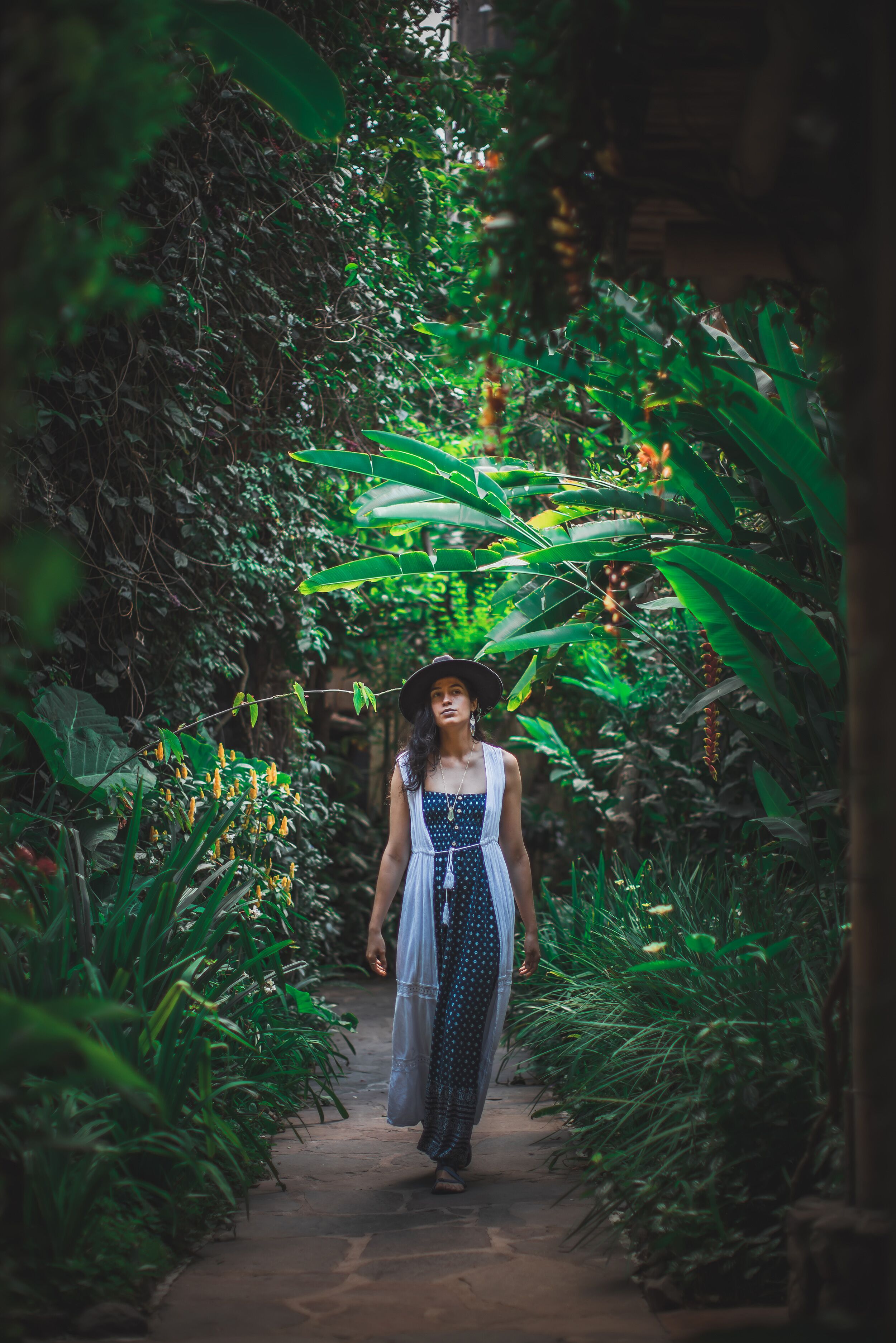 Ein Weg, umgeben von üppiger Vegetation, und eine Person in einem Punktekleid.