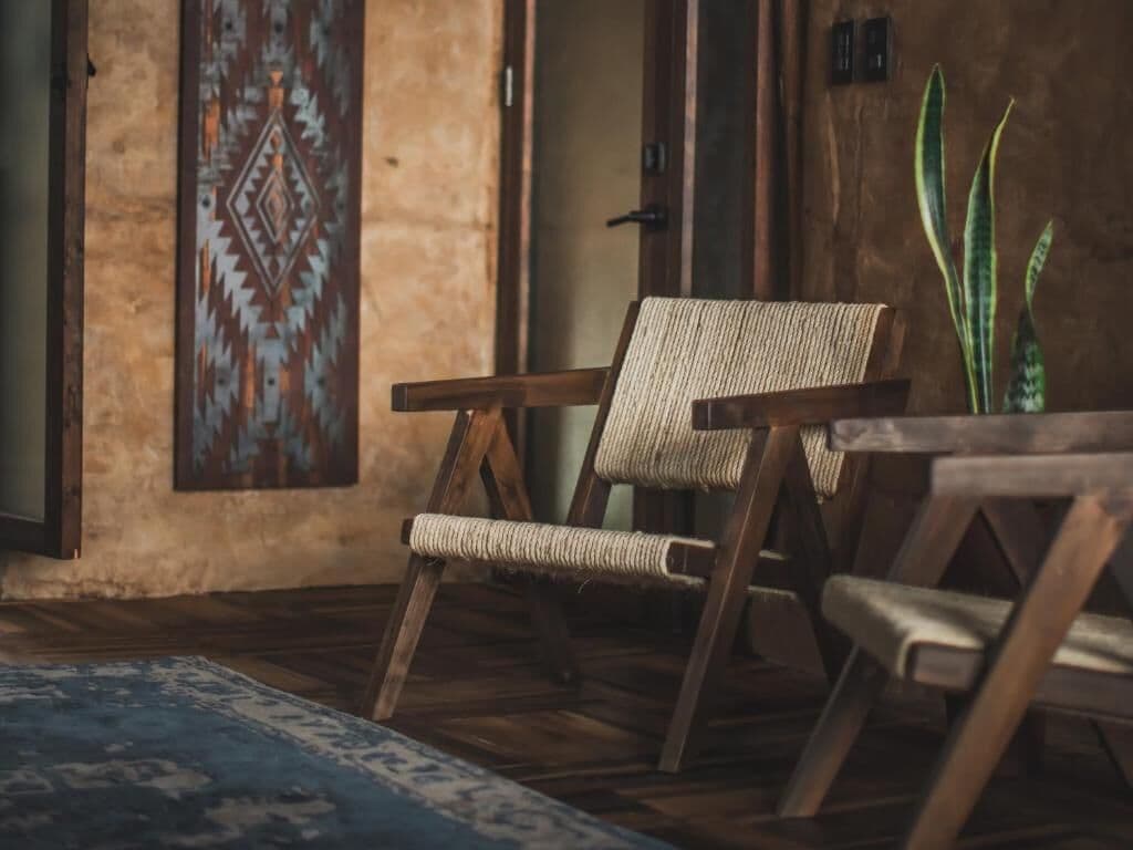 A rustic room with a woven chair, a patterned wall, and a potted plant.