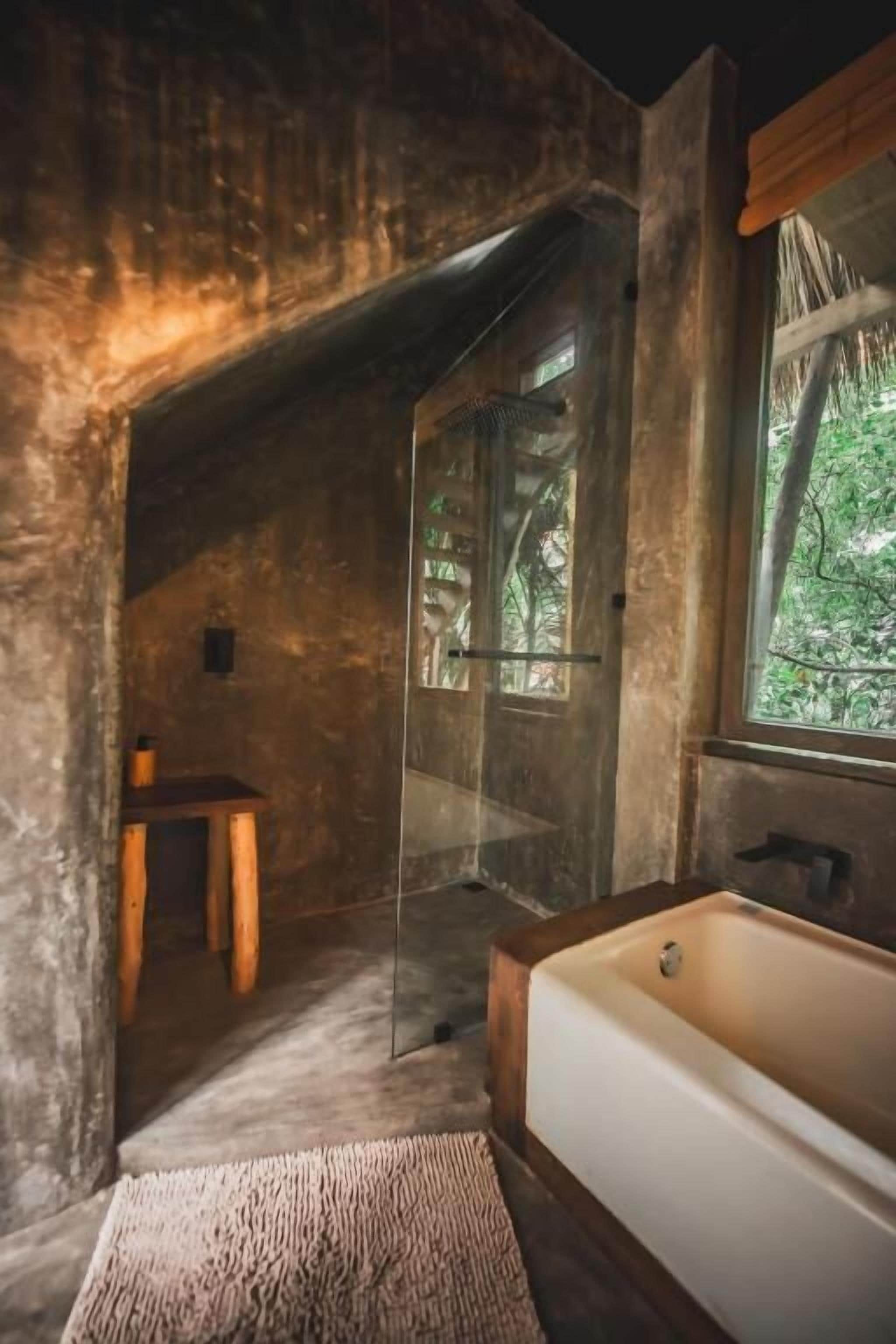 Un baño rústico con bañera, un taburete de madera y un box de ducha de vidrio.