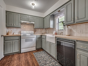 A kitchen with grey cabinets, a white stove, and a dishwasher.