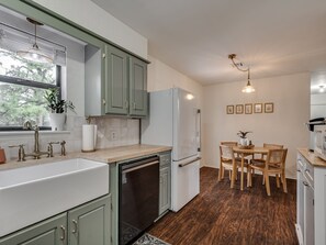 A modern kitchen with a sink, dishwasher, and dining area with chairs and a table.