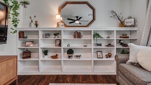 Un salon avec une bibliothèque blanche, une horloge et un canapé.